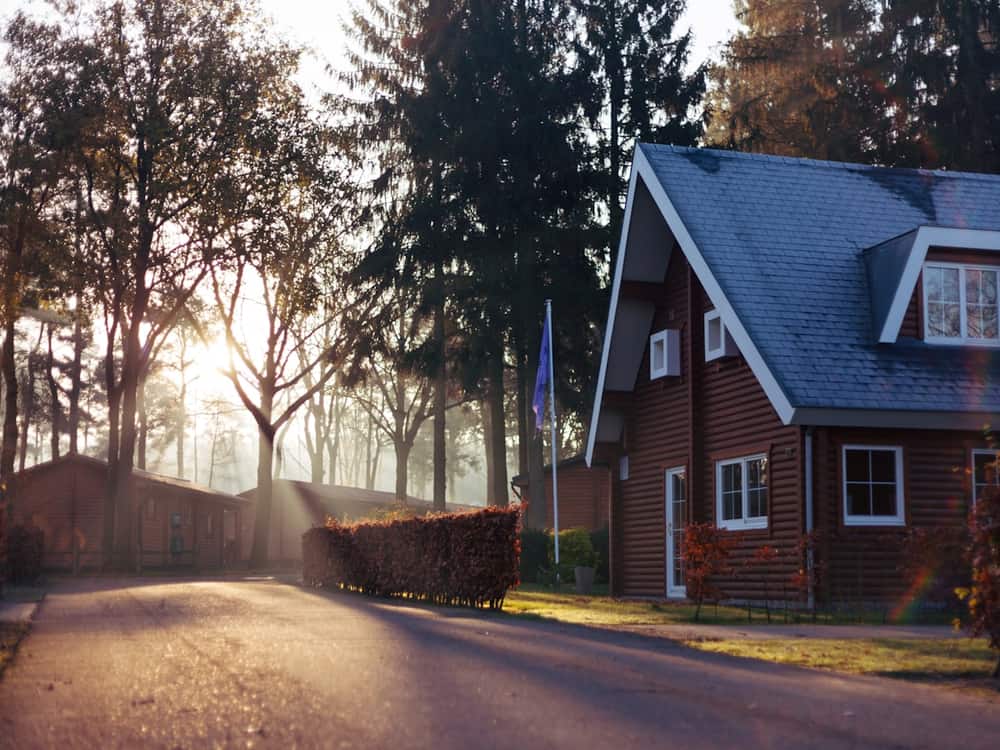 Casa rural de madera junto a un camino arbolado al amanecer